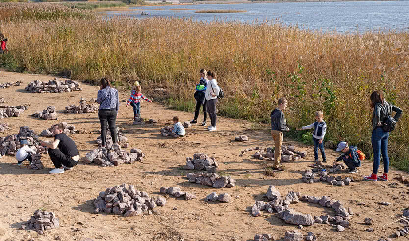 Дети и взрослые на берегу складывают камни – выпускные вечера для 4 класса от 4700 рублей