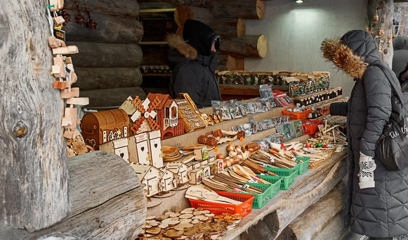 Женщина покупает сувениры. Парк «Рускеала» – новогодние туры в Карелию от 32400 рублей